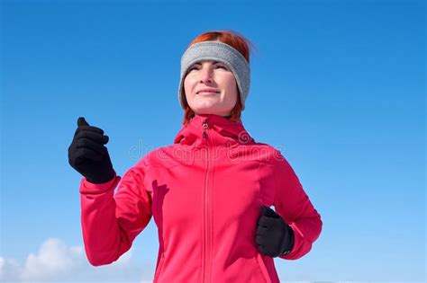 running athlete woman sprinting during winter training outside in cold snow weather close up