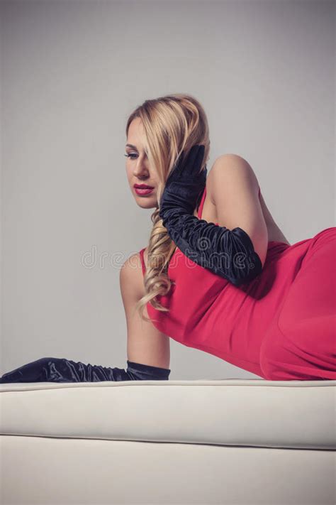 Seductive Blonde Woman In Red Dress Sitting On Chair Stock Image