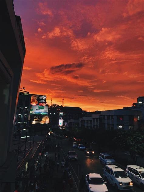 Cars Are Parked On The Street As The Sun Sets In The Sky Over Buildings