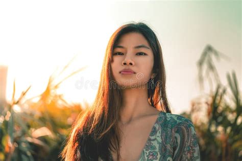Chinese Woman With Tanned Beauty Skin Portrait In A Green Garden With