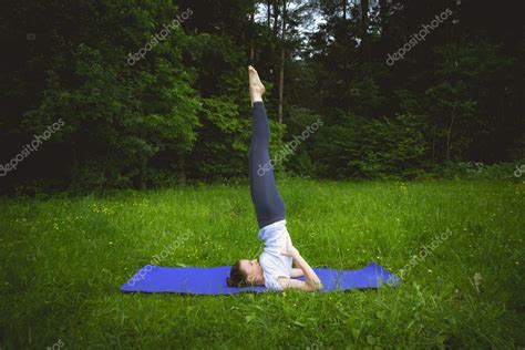 Молодая женщина практикующая йогу в парке Йога Саламба Сарвангасана стоковая фотография