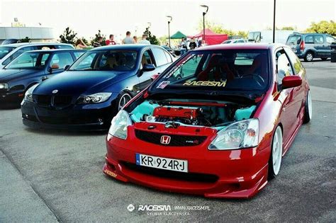 A Red Honda Civic Is Parked In A Lot With Other Cars And People Around It
