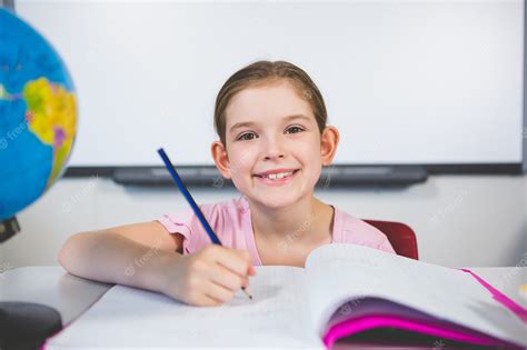 Premium Photo Portrait Of Smiling Schoolgirl Doing Homework In Classroom