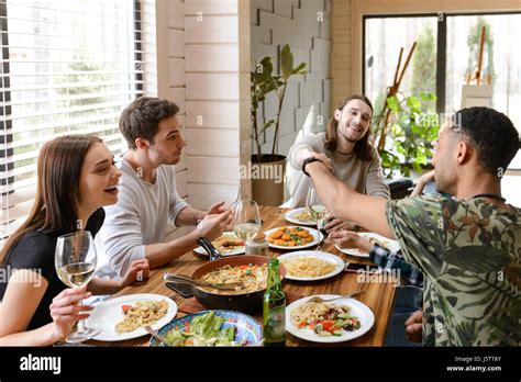 Group Of Cheerful Young Friends Eating And Having Fun At The Table At