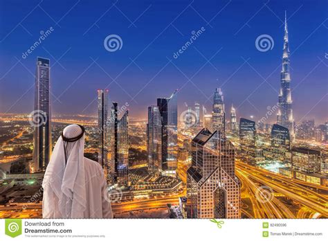 Arabian Man Watching Night Cityscape Of Dubai With Modern
