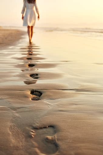Woman Walking Barefoot On Wet Shore Leaving Footprints In Sand Stock