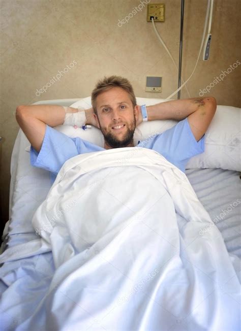Young American Man Lying In Bed At Hospital Room Sick Or Ill But