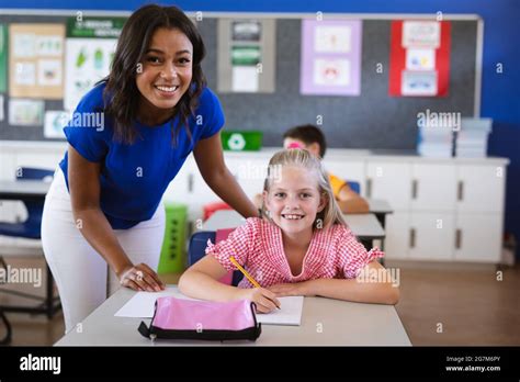 African American Female Teacher And Caucasian Girl Smiling In The Class At Elementary School