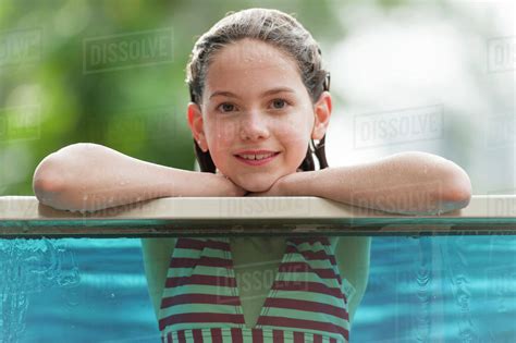 Girl In Bikini Leaning On Edge Of Swimming Pool Smiling Portrait Stock Photo Dissolve
