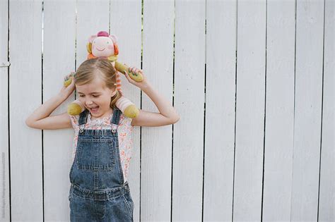 Young Girl Holding Doll On Neck By Stocksy Contributor Kristin