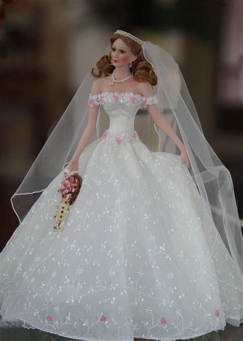 a barbie doll wearing a wedding dress and veil with flowers on the skirt holding a bouquet