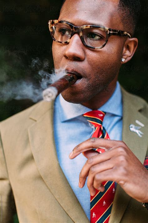 business man smoking a lit cigar by stocksy contributor kristen curette and daemaine hines