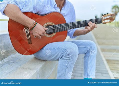 Young Hispanic Man Musician Playing Classical Guitar Sitting On Bench