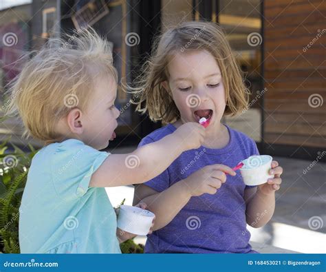 Two Young Children Sitting Outside And Sharing Ice Cream Stock Image