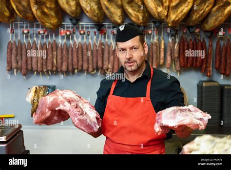 Portrait Of A Handsome Butcher Holding Meat Standing In A Butcher Shop