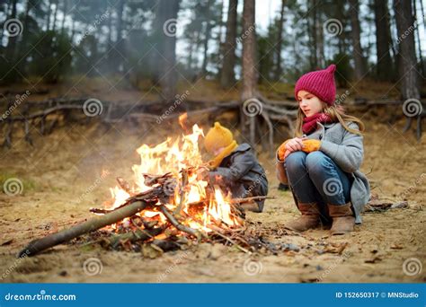 Two Cute Young Girls Sitting By A Bonfire On Cold Autumn Day Children