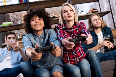 Multicultural Girls Playing Video Game On Sofa At Home Men Stock Photo