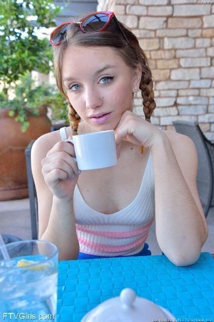 a woman sitting at a table drinking from a cup