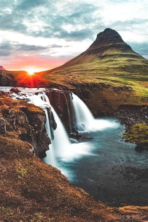 The Sun Is Setting Over A Waterfall In Iceland