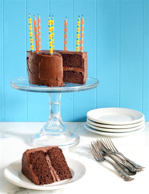 A Chocolate Cake With Lit Candles On It Sitting On A Glass Plate Next