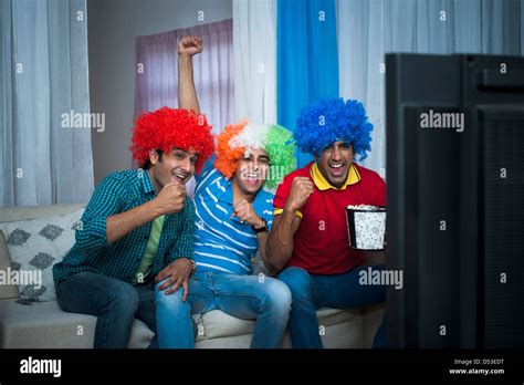 Friends Looking Excited While Watching Cricket Match On The Television