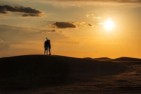 Silhouettes Of A Man And A Woman On Top Of A Sand Dune In The Sahara