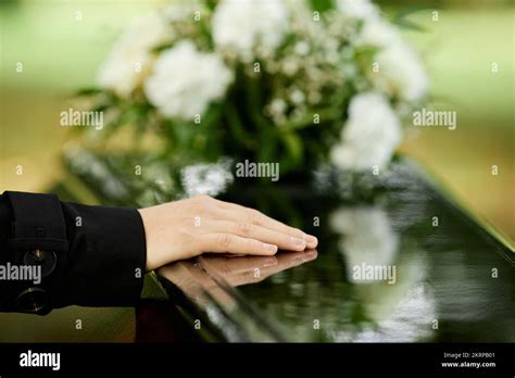 Close up of female hand on coffin saying goodbye at outdoor funeral