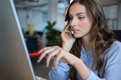 Businesswoman Working Over Computer While Talking On Mobile Phone At Desk Stock Image Image Of