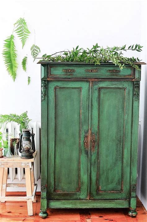 an old green cabinet with plants on top
