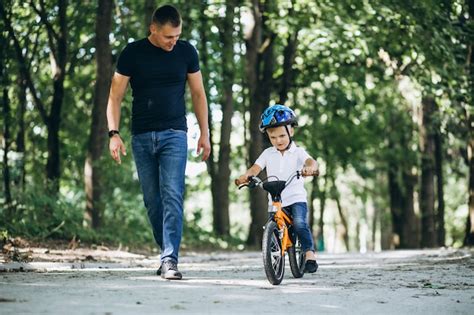 Padre Enseñando A Su Pequeño Hijo A Andar En Bicicleta Foto Gratis