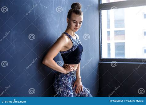 Beautiful Fitness Model Is Posing In Front Of The Dark Wall In A Dark Training Suit Stock Image