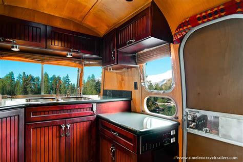 The Inside Of A Camper With Wood Cabinets And Counter Tops Windows