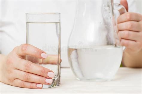A Female Is Pouring Fresh Clear Water From A Jug Into A Glass Health