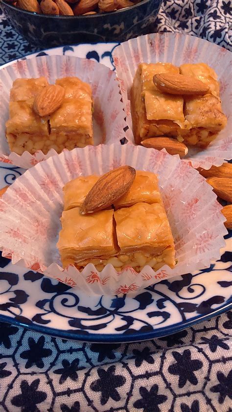 Four Pieces Of Almond Bars On A Blue And White Plate
