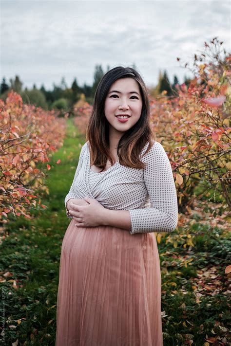 portrait of pregnant asian woman outdoor in a park by stocksy contributor take a pix media