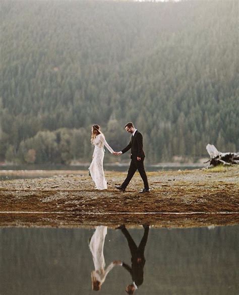 A Bride And Groom Holding Hands While Walking By The Water With