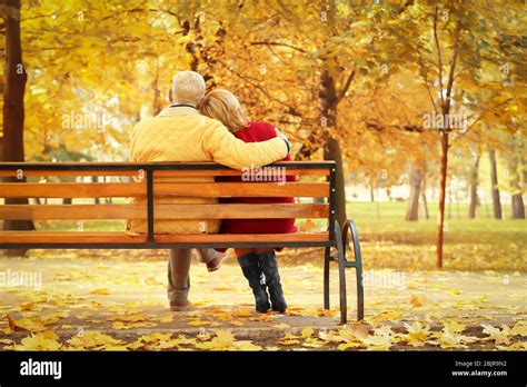 Elderly Couple Sitting On Bench In Autumn Park Stock Photo Alamy