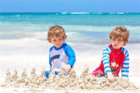Two Little Kids Boys Having Fun With Building A Sand Castle On Tropical