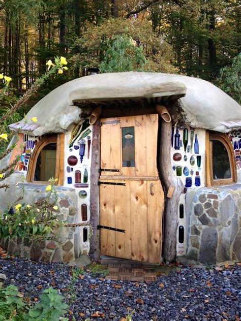 A Small House Made Out Of Rocks And Glass Bottles On The Outside