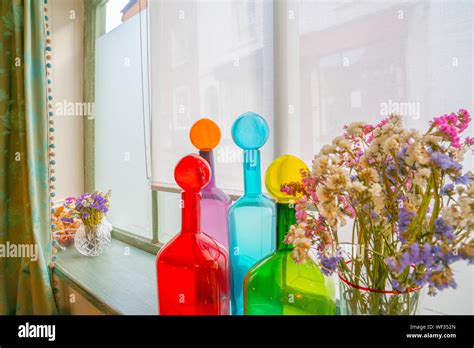 Mixed Colorful Bottles And Flowers On Window Sill Bright Red Blue