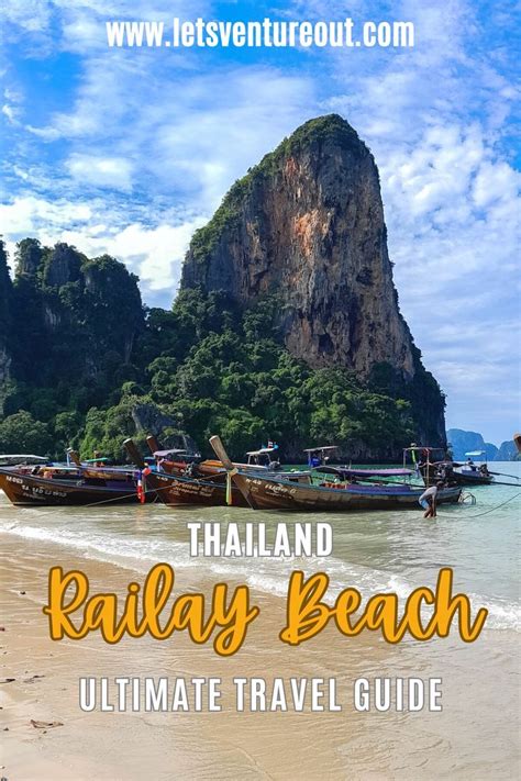 View Of Railay Beach Lined With Longtail Boats With A Limestone Cliff
