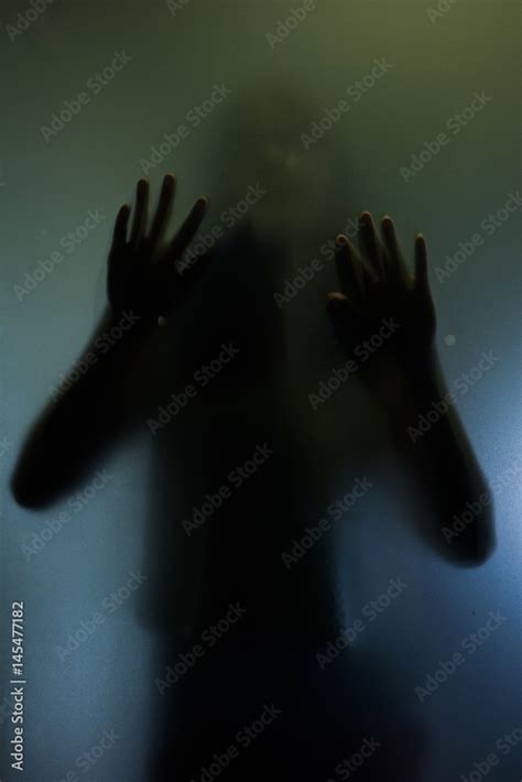 Trapped Woman Concept With Back Silhouette Of Hands Behind Matte Glass