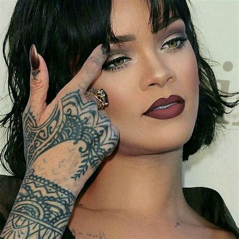 A Close Up Of A Person With Tattoos On Her Arm And Hand Near Her Face