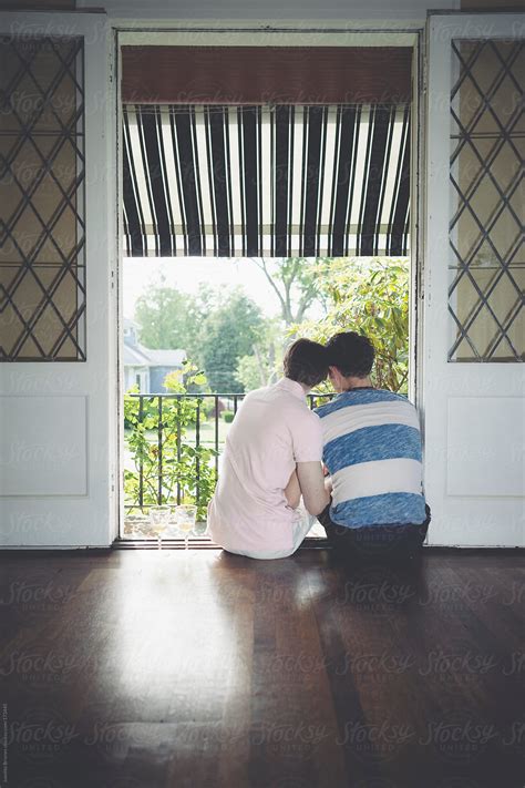 Male Gay Couple Sitting In The Balcony Of Their Home Looking Out To