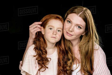 portrait of beautiful redhead mother and daughter posing together isolated on black stock