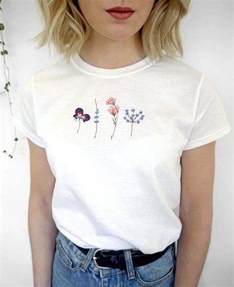 a woman wearing a white t shirt with flowers on it