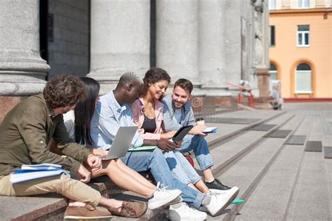 Group Of Students With Gadgets Sitting On The Steps Stock Photo