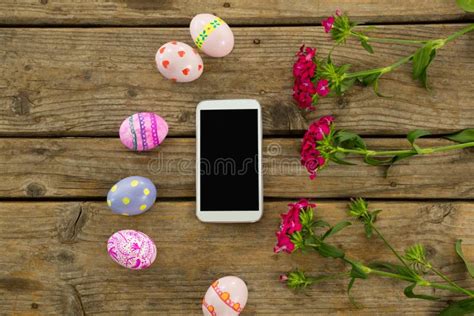Painted Easter Eggs Flowers And Mobile Phone On Wooden Surface Stock