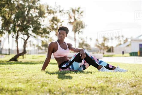 Slender African American Female Athlete In Colorful Activewear And White Sneakers Looking Away