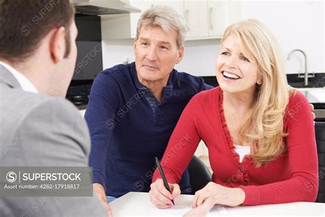 mature couple with financial advisor signing document at home superstock